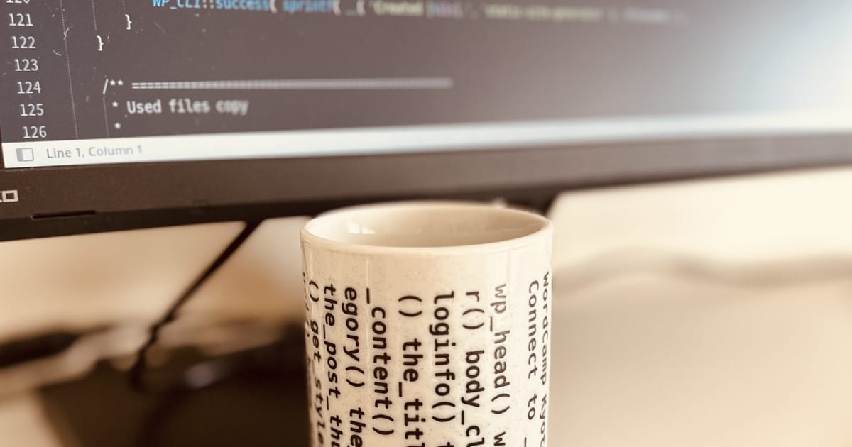 Program code displayed on a monitor beside a coffee cup